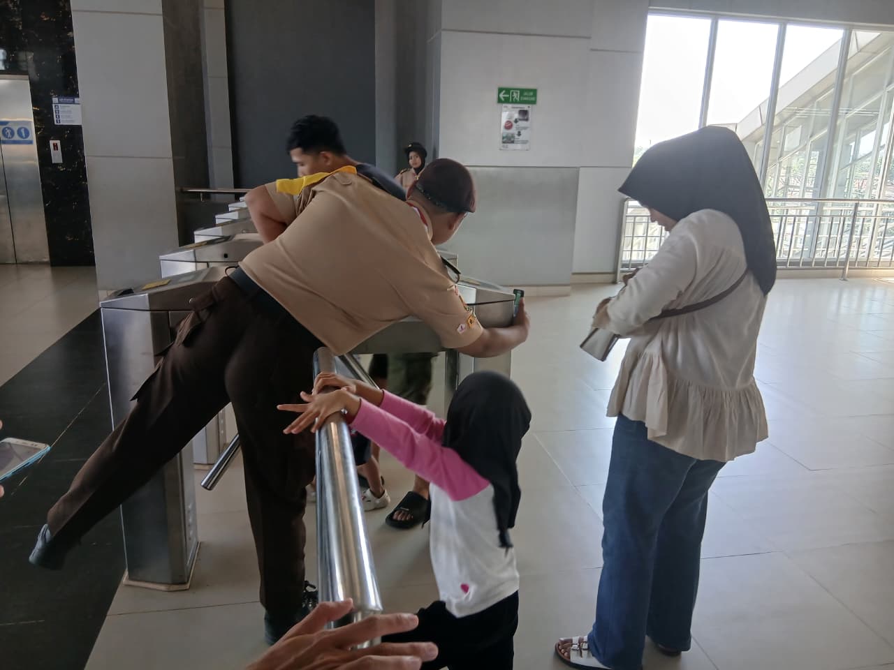 anggota pramuka putra membantu penumpang yang kesulitan untuk tap kartu