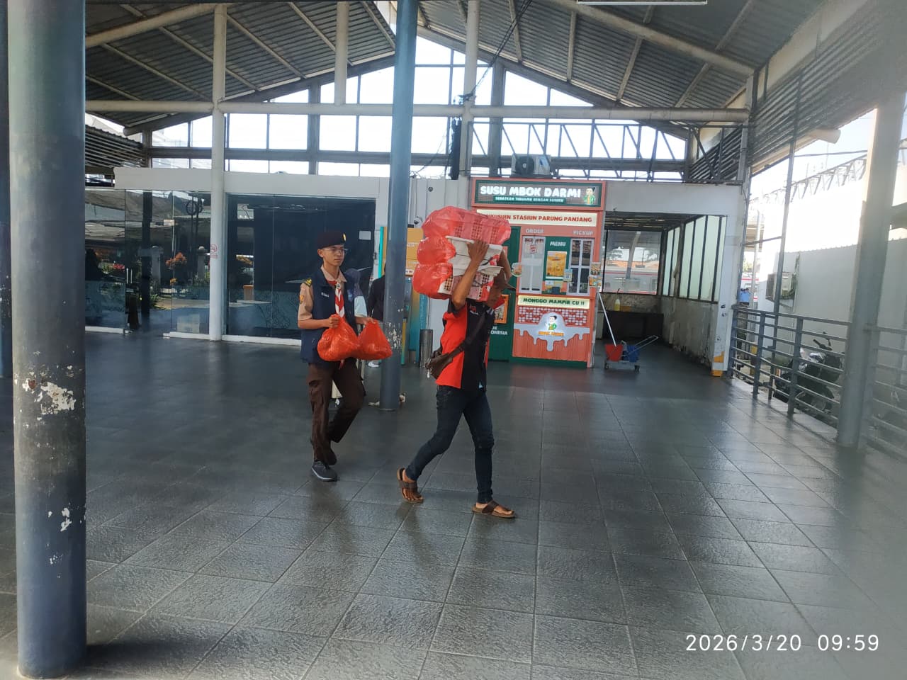 anggota warta pandu membantu penumpang krl yang kesulitan membawa barang