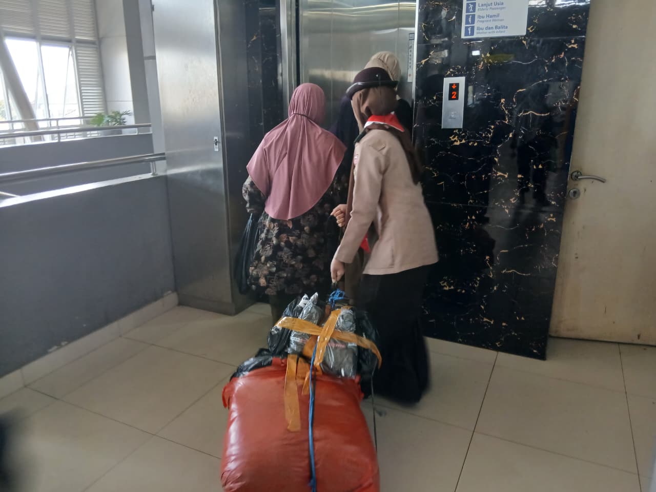 2 anggota putri membantu membawa barang penumpang yang kesulitan
